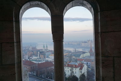 Buildings in city against sky seen through window