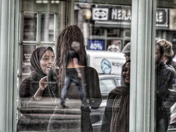 Portrait of a young woman looking through window