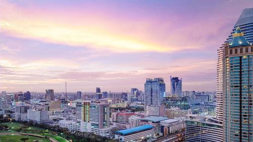 Modern buildings in city against sky at sunset