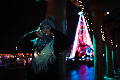 Full length of woman standing in illuminated christmas during winter at night