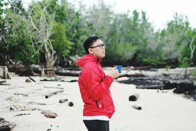 Full length of young woman standing by tree against sky