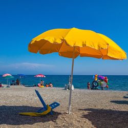 People on beach against clear blue sky