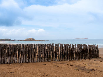 Wooden posts on beach against sky