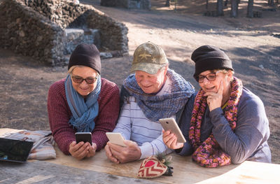 Senior man with friends using phones at forest
