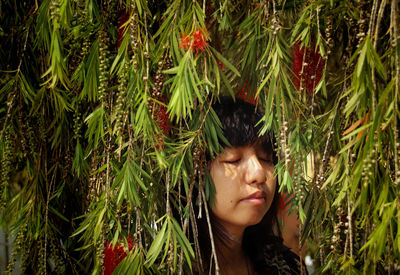 Beautiful woman with eyes closed by plants