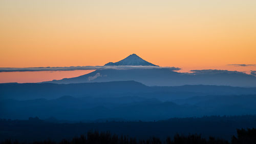 Scenic view of snowcapped mountains against orange sky