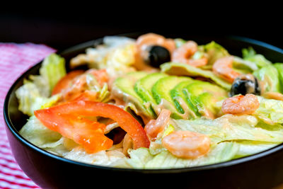 Close-up of salad with shrimps in container against black background