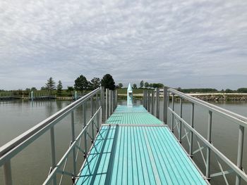 Footbridge over river against sky