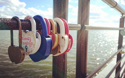 Close-up of love hanging on railing against sky