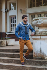 Full length of young man standing on staircase against building