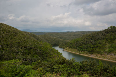 Scenic view of river amidst green landscape against sky