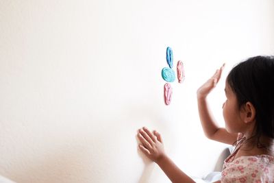 Side view of girl sticking clay on wall