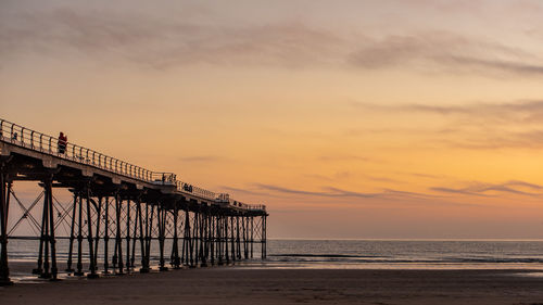 Pier over sea against sky during sunset