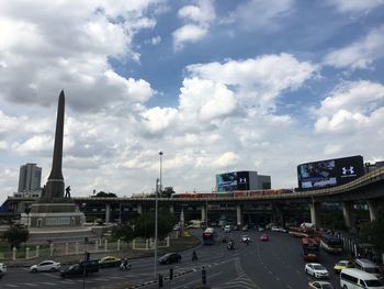 Traffic on road against cloudy sky