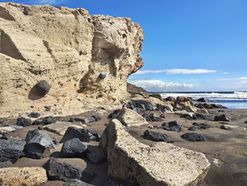 Rock formation on beach against sky