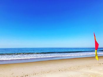 Scenic view of beach against clear blue sky