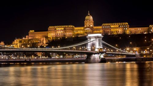 Illuminated bridge over river at night