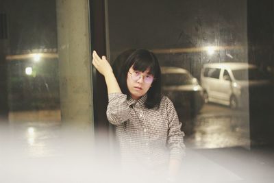 Portrait of sad young woman against glass window