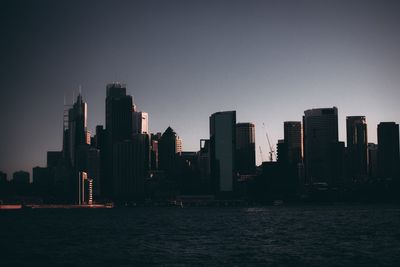 Modern buildings by sea against clear sky