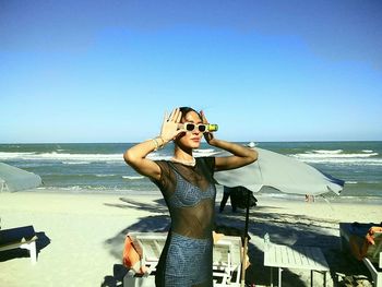 Rear view of woman standing at beach against sky