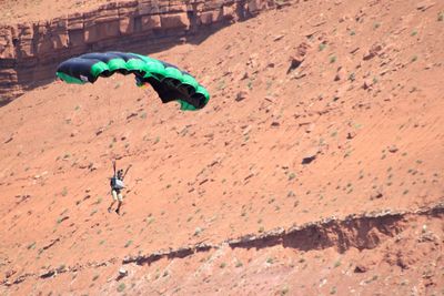 Man paragliding over rocky landscape at utah