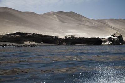 Scenic view of sea by mountains against sky