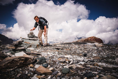 Full length of young man standing on rock against sky