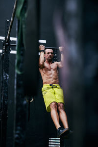 Shirtless fit young man working out in a cage at indoors gym