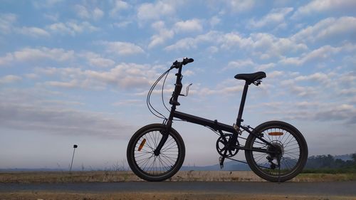 Bicycle parked on street against sky