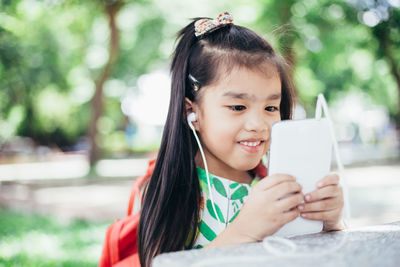 Close-up of happy girl holding mobile phone