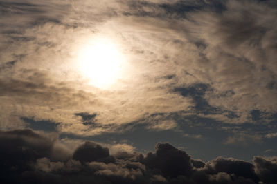 Low angle view of sun shining through clouds