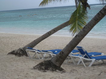 Deck chairs on beach against sky