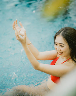 Portrait of young woman with arms raised standing at beach