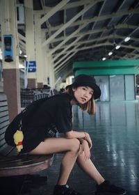 Full length of young woman sitting at railroad station platform