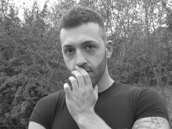 Portrait of young man standing against trees