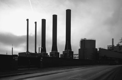 Factory by road against sky
