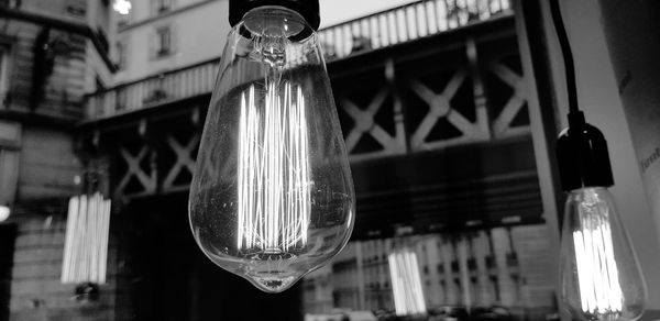 Low angle view of light bulbs hanging outside building