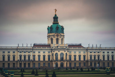 Statue in city against cloudy sky