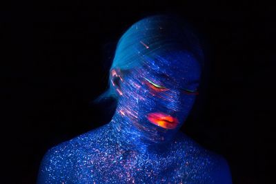 Close-up of female model with face paint against black background