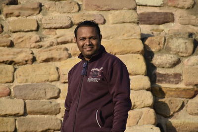 Portrait of young man standing against wall near harappan city 