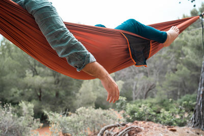 Man relaxing on hammock against trees