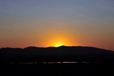 Scenic view of silhouette mountains against romantic sky at sunset