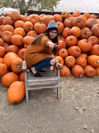 Portrait of young woman standing by pumpkins
