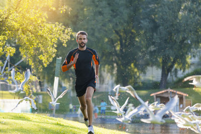 Man running at the riverside surrounded by seagulls