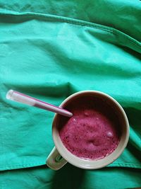 Directly above shot of red berry smoothie in mug on green fabric