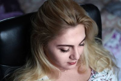 High angle view of woman with blond hair resting on chair