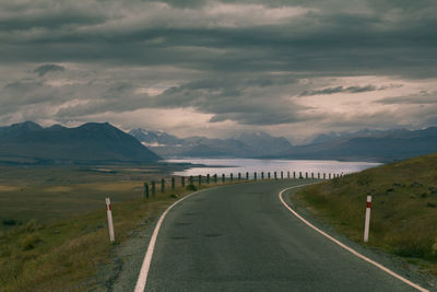 Road with a corner to the tekapo lake in new zealand with a cloudy sky