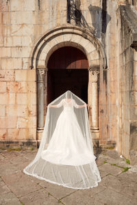 Rear view of woman with umbrella against white building