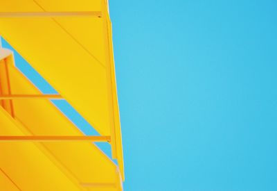Low angle view of yellow built structure against clear blue sky