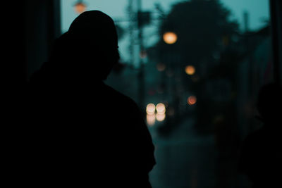 Rear view of silhouette woman standing on street at night